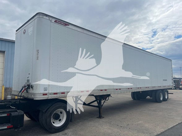 Great Dane sheet and post roll door trailer in a standing view showing front and side with hoist, landing gear, and three axles in a yard.