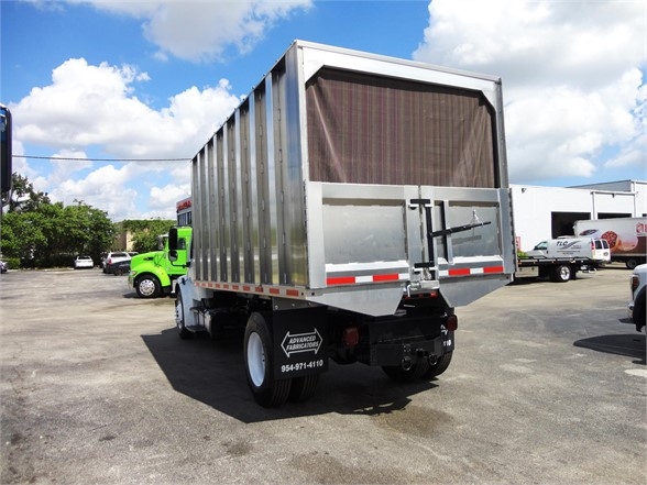 Rear view of a 2014 Freightliner BUSINESS CLASS M2 106 dump truck with silver dump body, dark mesh tailgate, and reflective tape on the back.