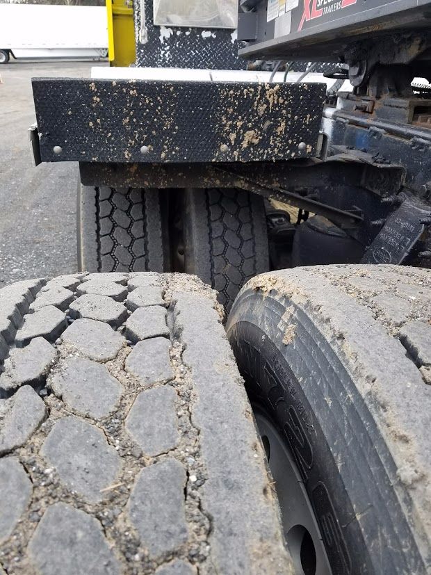Dual rear truck tires with mud and dirt, chassis, and a black rectangular toolbox above the axle; Peterbilt 389 listing context visible.