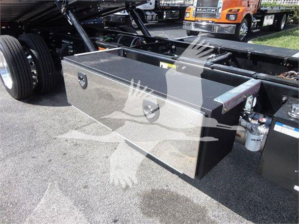 Truck chassis with a large rectangular metal toolbox mounted near the rear, visible fuel/water separator and engine components in background.