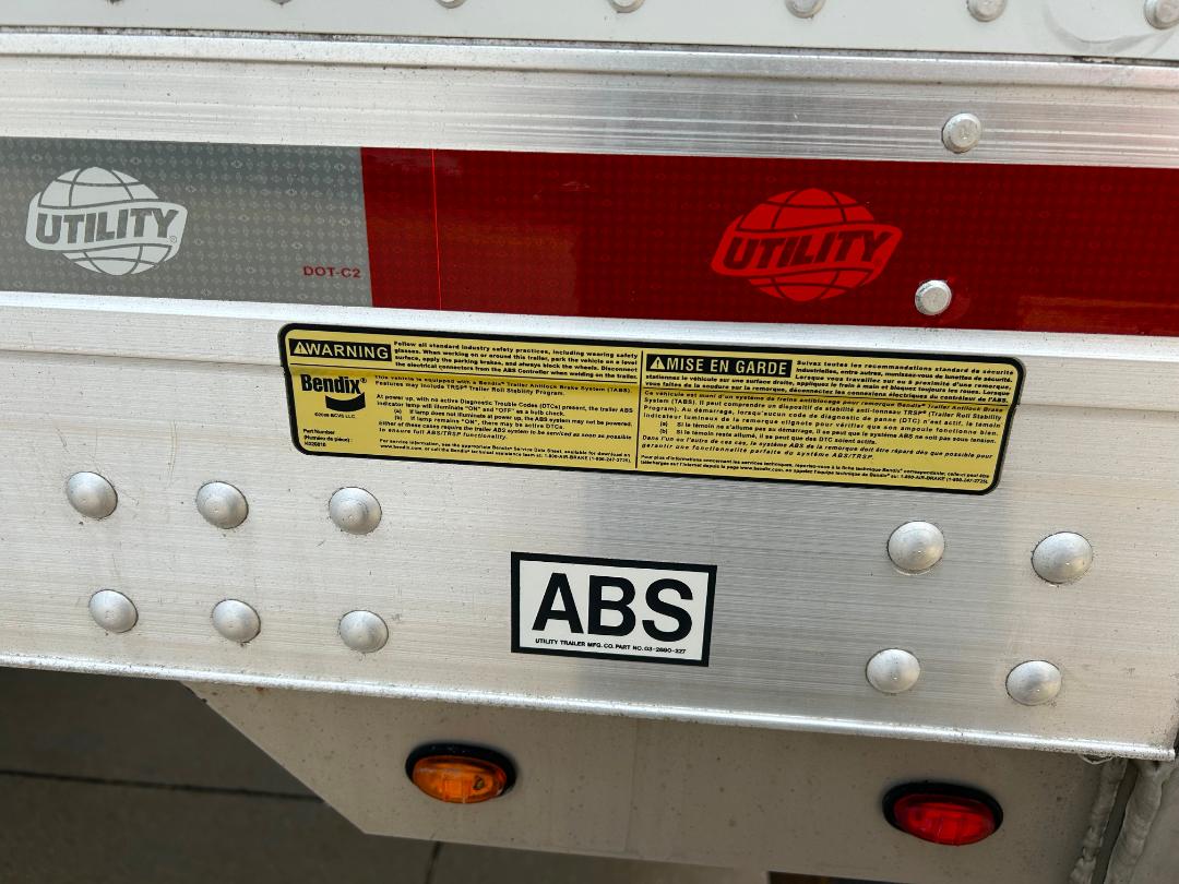 Rear of a 2020 Kenworth T680 truck trailer showing ABS sticker, warning label, Utility brand decal, and riveted aluminum skin.
