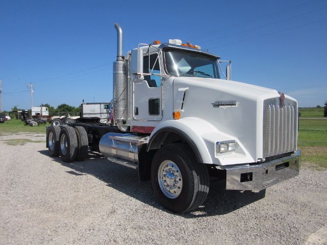 Kenworth T800 conventional daycab truck in a gravel lot with chrome exhaust stack and large grille.