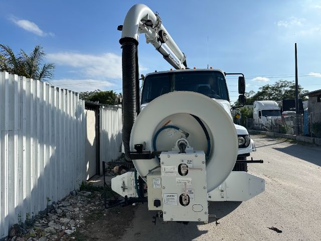 Vacuum truck with front-mounted hose reel and hydraulic arm on a 2016 Freightliner 108SD, showing large circular reel and control panel at the front.