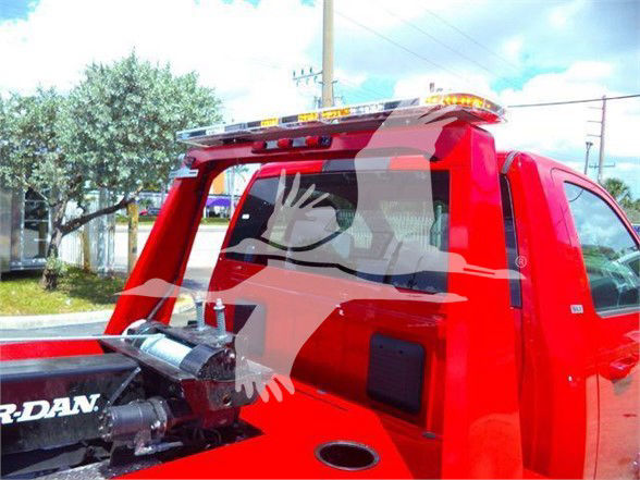 Ram 4500 tow truck rear cab area showing red body, hydraulic tow crane, and rear window with partial watermark graphic.