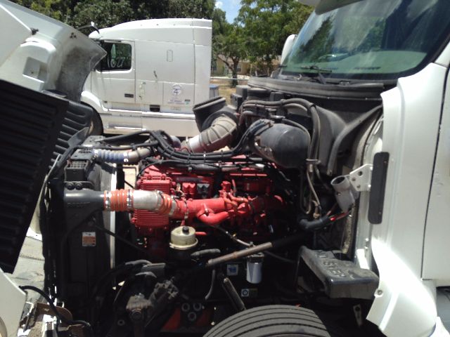Peterbilt VN truck engine bay with red engine and various hoses and components visible under open hood.