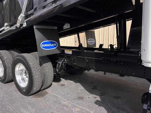 Freightliner Cascadia 125 dump truck undercarriage showing tandem rear axles and hydraulic piping.