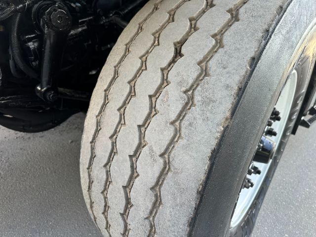 Truck front wheel and tire close-up showing tread wear and sidewall; part of undercarriage visible on left.