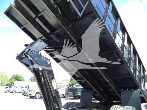 Dump truck bed in raised position with hydraulic lift and debris on ground, International DURASTAR 4300 signage not visible.