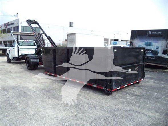 Truck bed trailer in a lot attached to a white cab with black dumping trailer.