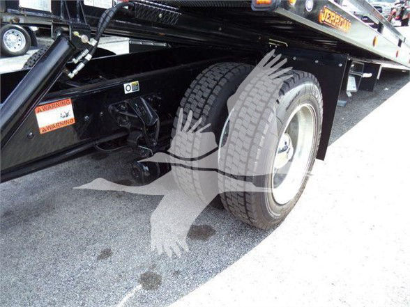 Kenworth T280 chassis showing rear wheel and frame with warning labels and undercarriage components visible.
