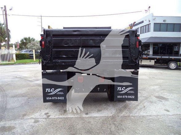 Rear view of a black dump truck bed with TLC decals on mud flaps and a faded watermark overlay across the image.