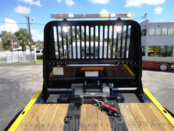 Kenworth W900 bed with Jerr-Dan tow setup, flatbed wood deck, rear view showing protective cage and winch area, yellow accents.