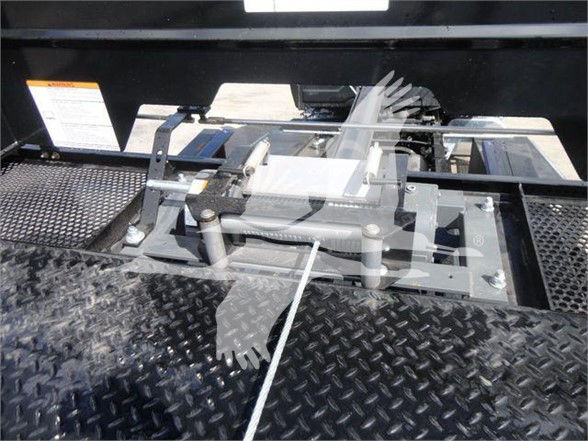 Truck bed hitch assembly and mounting hardware on a diamond plate surface with warning labels.