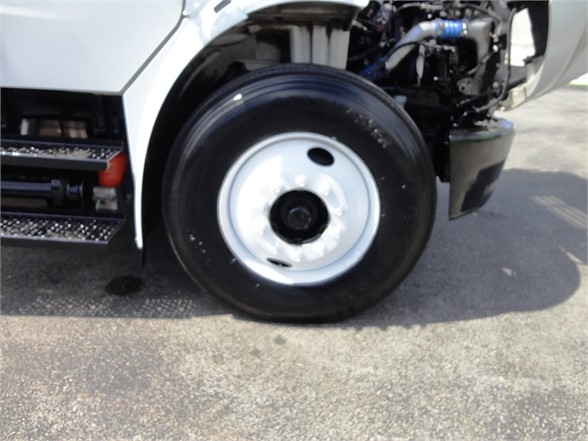 Freightliner M2 106 front wheel and partial engine bay showing wheel, fender, and tag area.