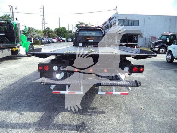 Truck bed with hydraulic lift and ramp on a Ford F-750 Tow truck; rear view showing platform, tail lights, and reflectors.