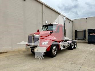 Kenworth T880 conventional daycab truck in red, front three-quarter view, on concrete lot.