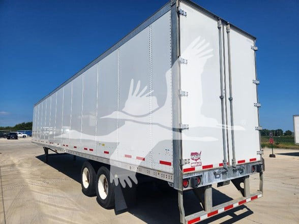 Trailer rear view showing white Wabash van trailer with double doors, reflective tape, and tandem axles.