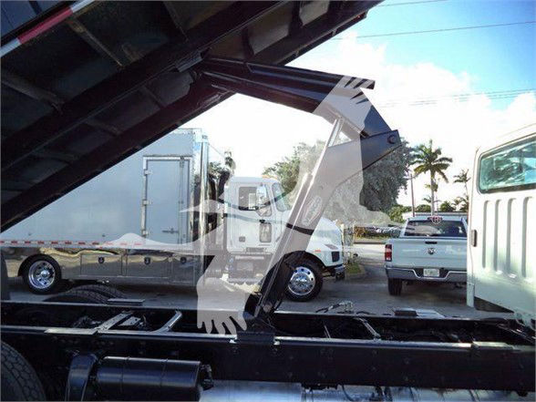 Truck cab and dump bed of a Freightliner M2 106 viewed from side with hydraulic lift arm visible in foreground.