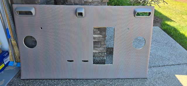 Volvo truck sleeper interior panel with cutouts and circular openings, rectangular hole, textured surface.