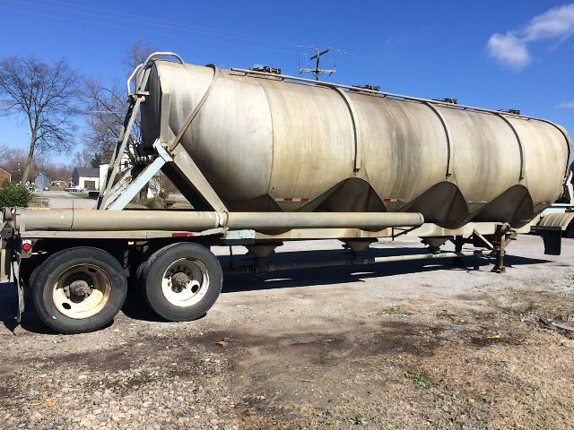 Pneumatic dry bulk trailer with cylindrical tank on steel frame, dual rear axles, weathered surface, VIN 1HLS1N7B5E7U00356 not visible on the image but listed.