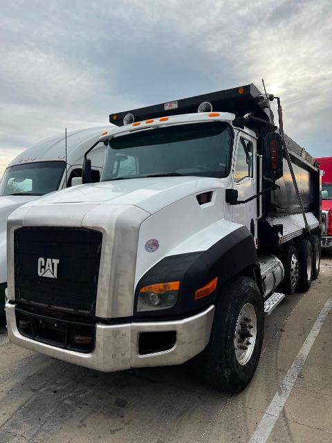 Cat T660S dump truck side/front view showing white cab, black grille, CAT logo, and dump bed in a parking lot.