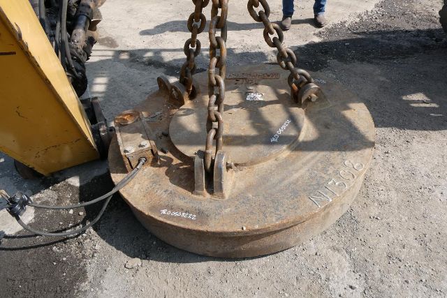 RK Magnetics 57 clamshell scrap magnet and chain lifting attached to yellow machinery, round metal magnet with chains and hooks.