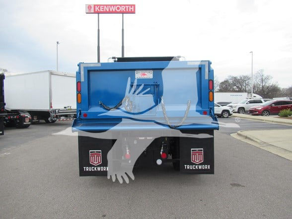 Kenworth T380 dump truck rear view with blue bed and painted hand graphic, two mud flaps with TruckWorx logos, safety chains, in a dealership lot.