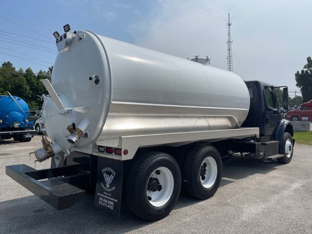 Truck-mounted vacuum tanker with cylindrical stainless steel tank on Freightliner M2 chassis, rear inlet, valves, and dual rear axles.
