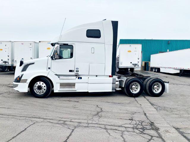 Volvo VNL 670 conventional sleeper tractor in white, side view with sleeper cab and dual rear axles, parked in a lot.