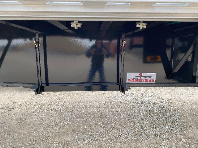 Trailer undercarriage with black metal surface and a small label reading 'PLACE SINGLE COIL HERE' near a hitch area.