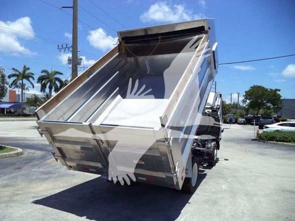 Isuzu NQR dump truck with bed raised showing rear and side, chrome metallic finish and hydraulic tilt mechanism.