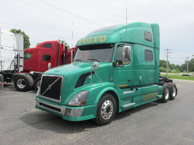 2012 Volvo 780 conventional sleeper tractor in teal green with Volvo lettering on the cab, parked in a lot.