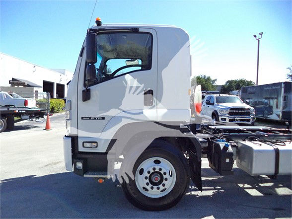 Isuzu truck cab side view with front wheel, fuel tank, and chassis visible. No visible text on the cab clearly readable.