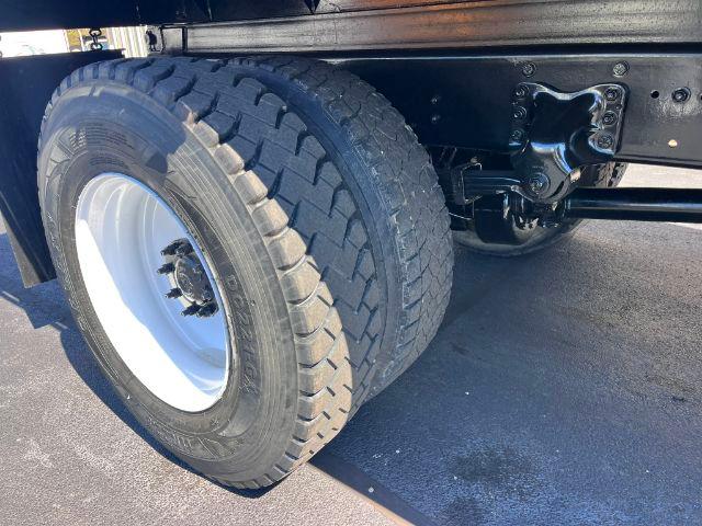 Truck rear dual tires and suspension undercarriage of a Freightliner M2 106 dump truck showing heavy-duty dual tires and rear axle components.