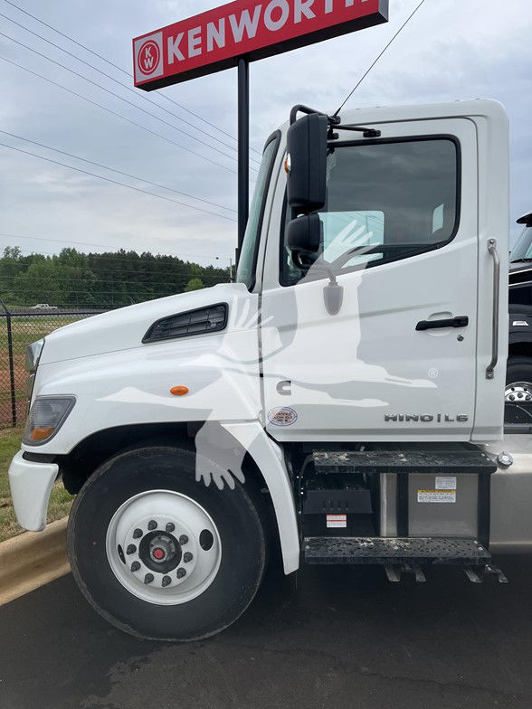 2026 Hino L6 cab and chassis side view with Kenworth sign in background.