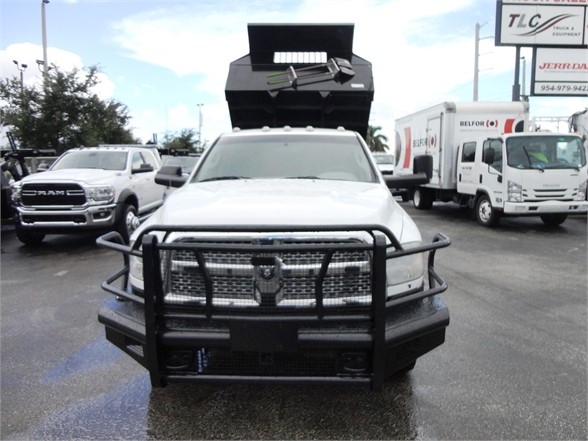 Ram 3500 SLT dump truck with front grille guard, white cab, dump bed raised in background.