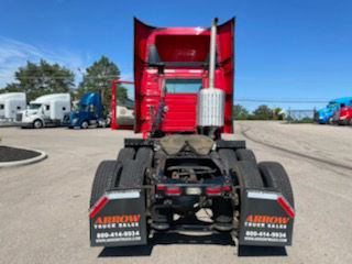Rear view of a Volvo VNM64T-200 conventional daycab tractor showing dual rear axles, mud flaps with 'Arrow Bow' branding, and trailer hitch area.