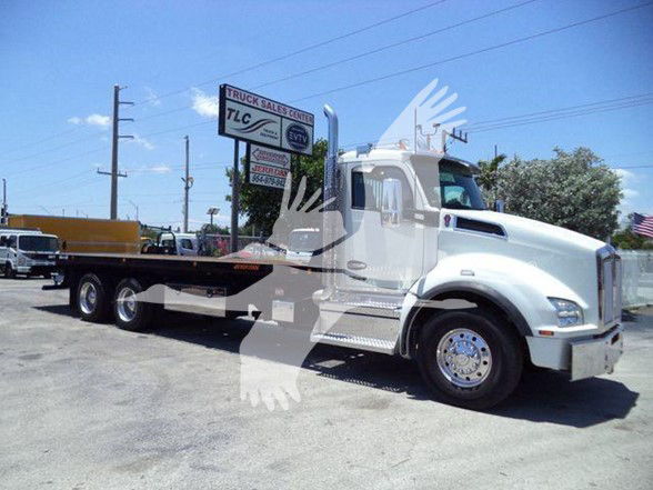 Kenworth T880 flatbed tow truck side view with long hood and chrome bumper in dealership lot.