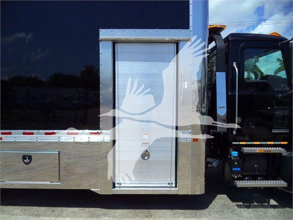 Tow truck side body with a storage compartment door and steps, featuring a metallic panel and black cab visible on the right.