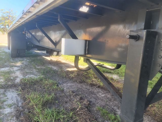 Trailer underside showing frame and landing gear of a 48x102 utility flatbed trailer, with a white rectangular box/toolbox and black metal beams.