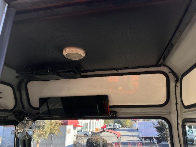 Cab interior of a 2013 Tico PROSPOTTER DOT truck showing ceiling panel, a circular vent or speaker, and rear window with roadside view.