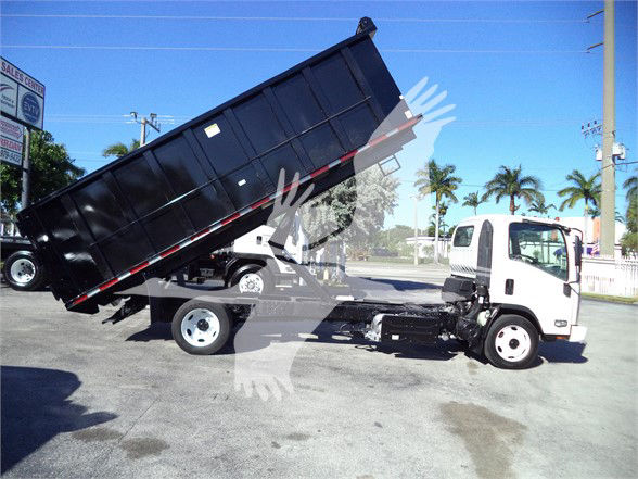 Isuzu NRR dump truck with its black dump bed raised, white cab, in-service condition; visible wheels and hydraulic lift under bed.