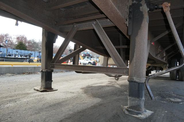 Trailer undercarriage showing legs and support beams of a curtainside trailer.