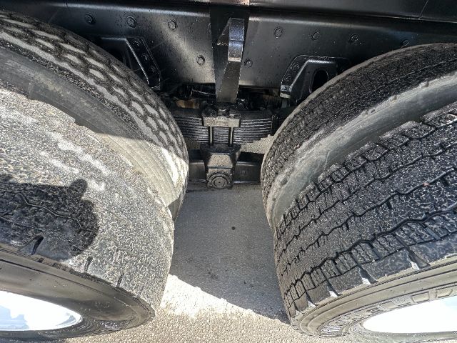 Freightliner cabover/truck rear axle view showing tandem wheels and suspension, with leaf springs and differential housing visible between tires.