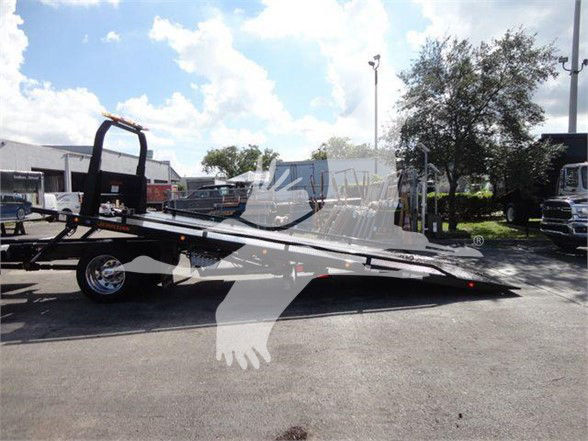 Tow truck trailer with hydraulic tilt-bed in a dealership lot. No legible labels or readable text on components.