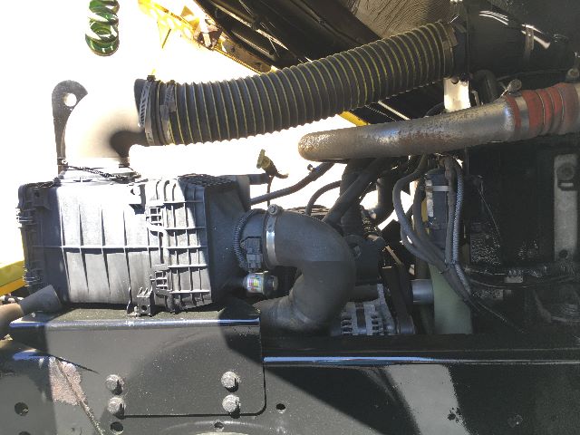 Industrial truck engine bay with hoses, air filter housing, and various hydraulic lines visible. Text on components not clearly legible.