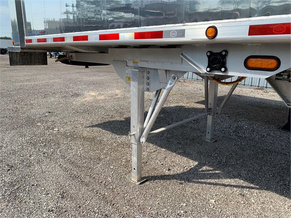 Trailer landing gear and suspension of a 2023 24ft aluminum dump trailer with top hinge door, visible stock number 058948, side markers, and support beams.