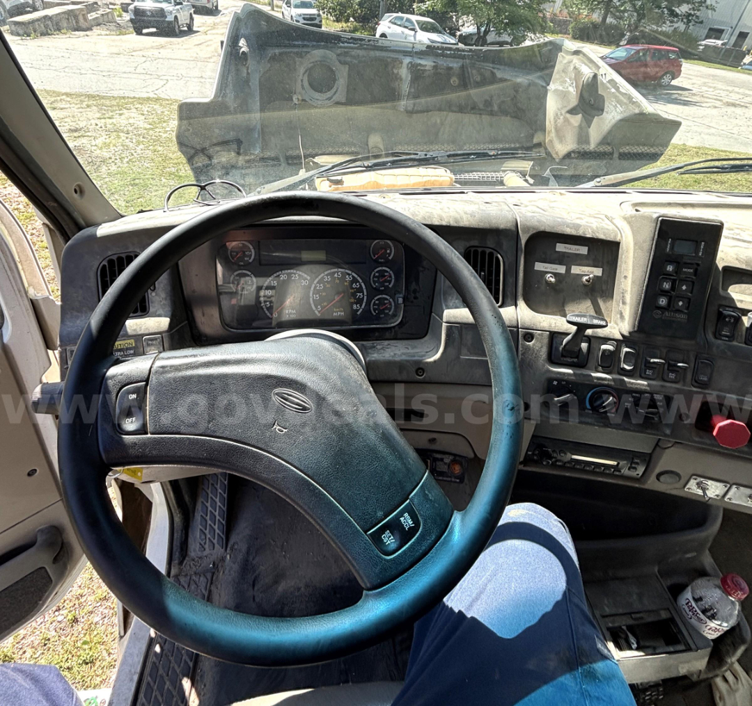 Trucking cabin dash and steering wheel in a Sterling LT9500 cab; dashboard gauges visible with worn interior; gear shifter panel and various switches on right.