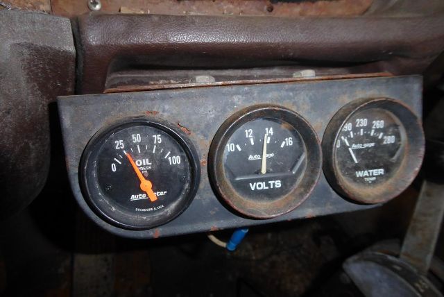 Dashboard gauges showing oil pressure, volts, and water temperature in a Ford 8000 truck cab and chassis.