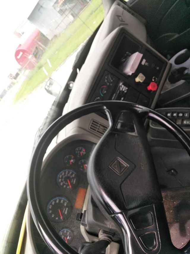 Interior of a truck cab showing steering wheel, gauge cluster, and dashboard controls. There are various dials and a central console with switches. No clear part numbers or fluid labels visible.